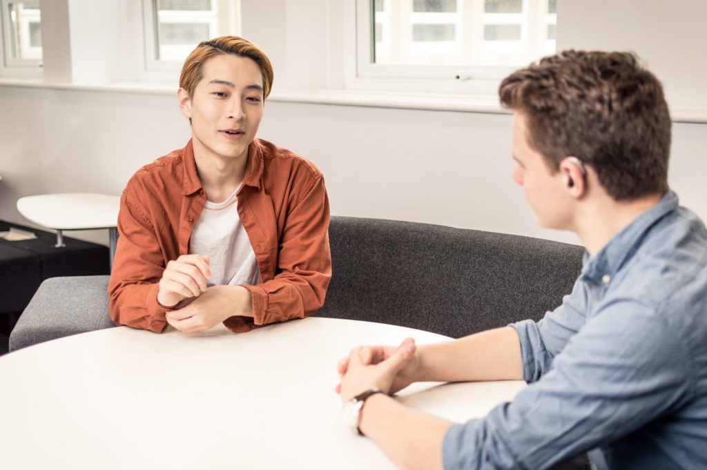 Two young men sat at a table talking